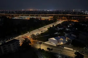 A nighttime aerial view of a city street with illuminated vehicles and buildings.