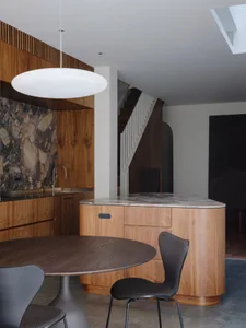 Modern minimalist kitchen featuring wooden cabinets and countertops with a marble backsplash.