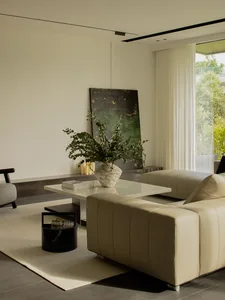 A modern interior living room with contemporary furniture, including a leather couch, marble coffee table, and decorative pla