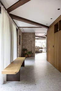 Modern interior space featuring a wooden bench, stone walls, and large windows.