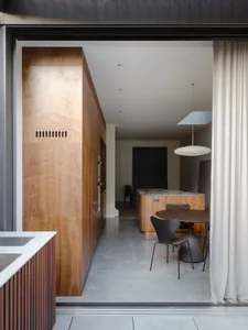 Modern kitchen featuring wooden cabinets and table with a hanging lamp.