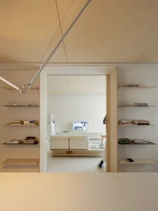 A modern living room with white walls, wooden shelves, and a white sofa.
