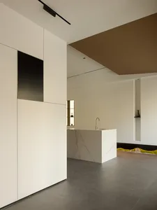 Modern kitchen with white marble countertops and white cabinetry.