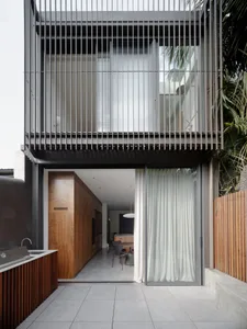Modern minimalist entryway featuring a kitchen with metal framing, glass curtains, and concrete flooring.
