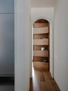 Modern minimalist wooden shelf with curved design and minimal objects.