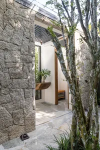 A modern, minimalist outdoor patio area with stone walls and a wooden bench.