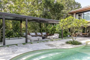 An outdoor living space featuring modern furniture, stone and concrete elements, surrounded by greenery.