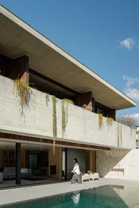 A modern residential building with a concrete exterior and a large pool.
