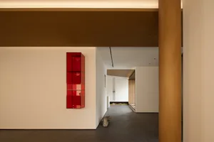 A modern interior with minimalist design elements, featuring a red, contemporary display case.
