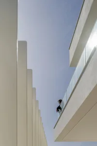 A modern balcony with glass balustrade overlooking a clear blue sky.