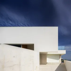 A minimalist, modern residential structure featuring white walls and a concrete patio.