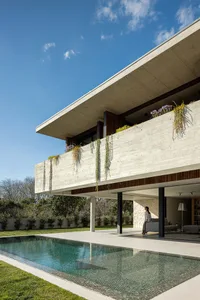 A modern house with a concrete exterior and green plants on the balcony.
