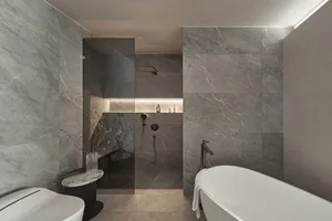 Modern bathroom with marble walls and white freestanding bathtub.