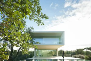 A minimalist house featuring large glass windows and a contemporary white facade.