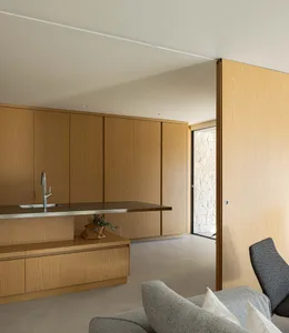 A modern, minimalist kitchen featuring wooden cabinets and a sleek, stainless steel countertop.