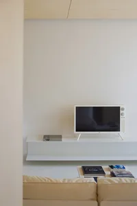 A minimalist living room with a white floating shelf.