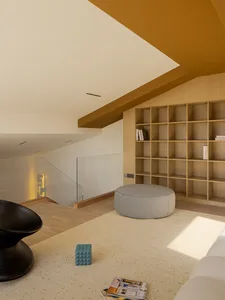 Modern minimalist living room featuring a wooden shelf, round pouf, and a geometric pattern on the rug.