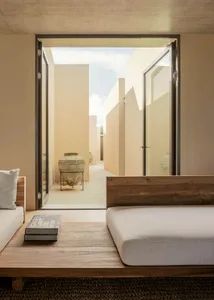 Modern bedroom with neutral colors, concrete walls, wooden floor, and concrete furniture