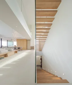 Modern residential interior with white walls, wooden stairs, and a combination of concrete and glass elements.