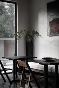 A minimalist industrial interior featuring concrete walls and wooden furniture.