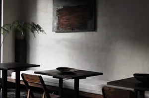 A minimalist restaurant interior featuring concrete walls and wooden furniture.