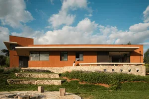 A modern house with a clay exterior, featuring a wide overhang and large windows.