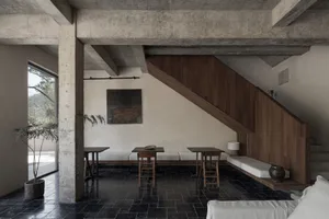A modern residential interior with exposed concrete beams and dark stone tiles.