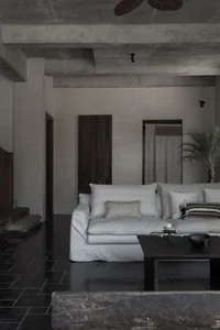 Contemporary living room with minimalist design, concrete flooring, and sleek white furniture.
