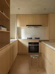 Modern kitchen with minimalist wooden cabinets, countertops, and flooring.