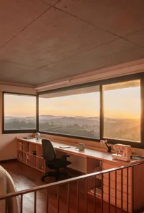 Modern office setup featuring a minimalist desk with a black swivel chair, a shelf with books and a globe, and a sewing machi