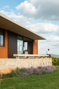 A modern residential exterior featuring stucco, stone, and concrete materials.