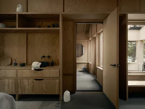 Modern, minimalist residential interior with wooden walls, shelves, and floor.