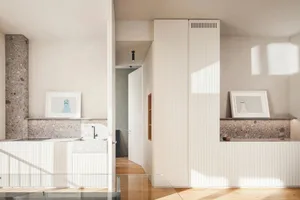 A minimalist kitchen with terrazzo countertops and white cabinets.