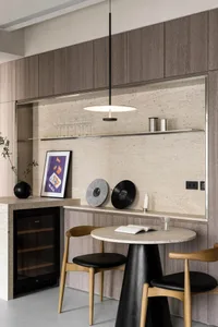 A modern dining zone featuring wooden chairs, a round table, orange and purple artwork, and a marble backsplash.