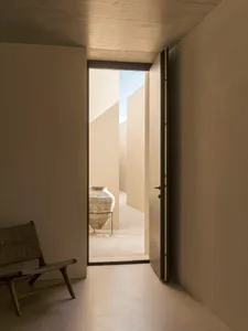 An open doorway into a minimalist, concrete-themed interior space.