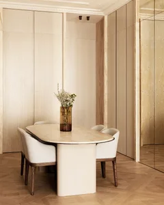 A modern dining room with a marble table and chairs, featuring a vase of flowers.