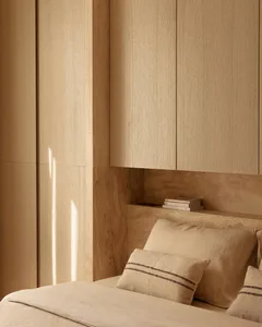 Minimalist bedroom with wooden paneled walls and beige bedding.