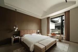 A minimalist bedroom with a wooden headboard, white bedding, and modern lighting.