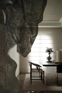 A modern dining room with a textured fabric screen, wooden chairs, and a bonsai tree on a polished dining table.