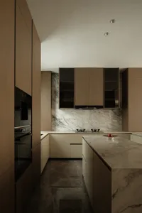 A modern residential kitchen featuring marble countertops and subway tiles on the floor.