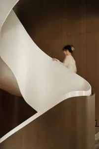 A modern, white staircase with a white railing curves elegantly.