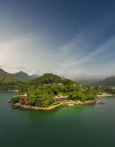 A picturesque residential vacation home nestled amidst lush greenery and surrounded by water, featuring natural materials.