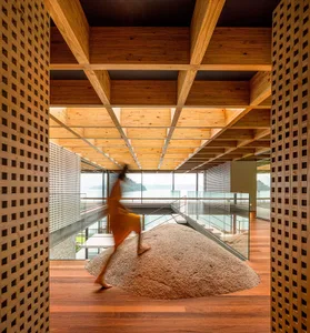 Person walking on a stone in a minimalist wooden interior design space with a view of the ocean.