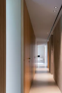 A minimalist corridor with wooden closets and a white floor.