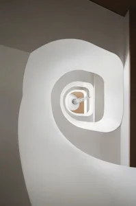 A minimalist white staircase with curved steps and a central light fixture.