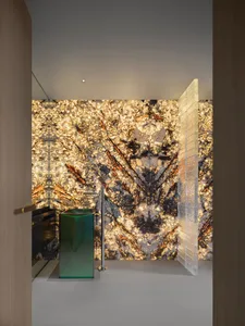 Modern bathroom interior with illuminated marble walls and green glass pedestal sink.