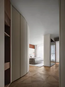 A modern bedroom featuring wood flooring and minimalist furniture.