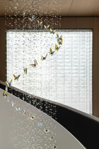 A contemporary glass chandelier sculpture hanging from the ceiling in an elegant interior space.