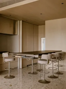 Modern kitchen with concrete countertop, featuring minimalist design and high stools for seating.