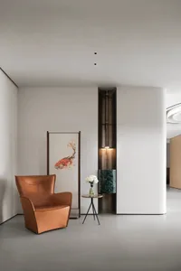 A modern living room with a leather armchair and marble accent wall.